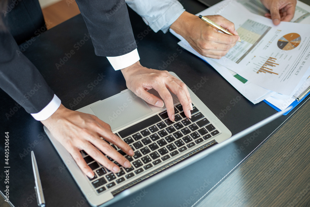 Poster close up asian businessman using laptop computer analysis documents and graph financial diagram on o