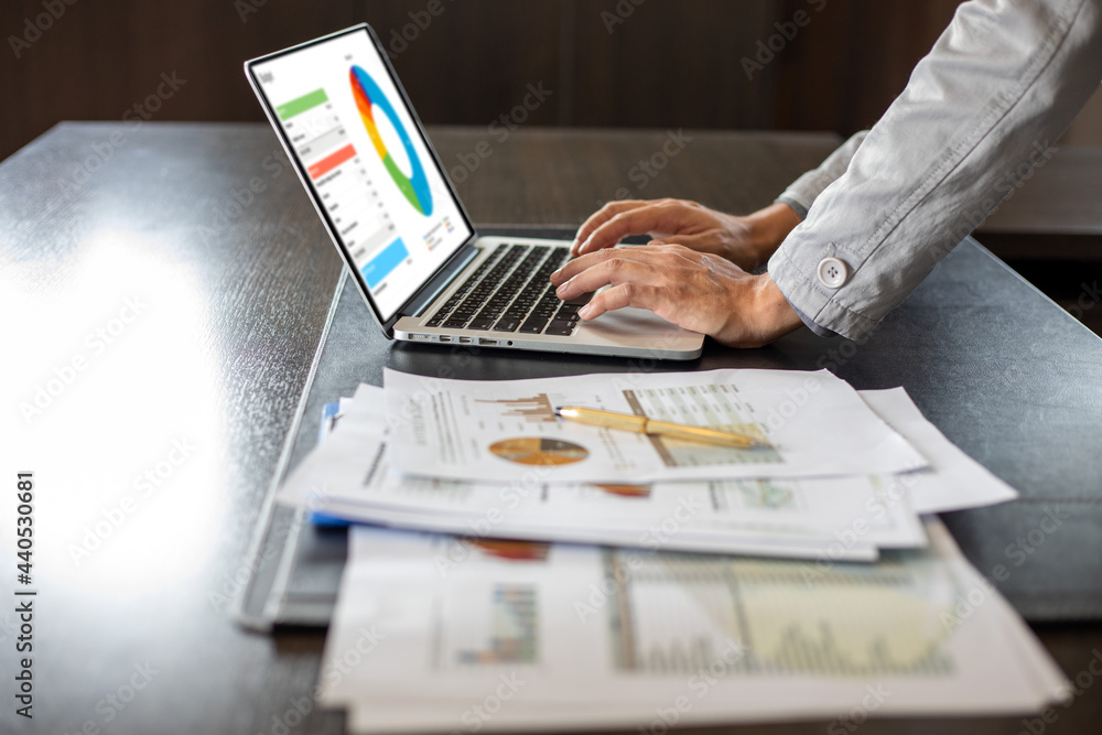 Poster close up asian businessman using laptop computer analysis documents and graph financial diagram on o