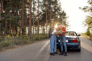 Two women trying to find the way on map near cabriolet