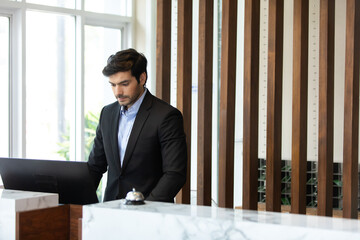 Friendly handsome man hotel receptionist in a stylish luxury hotel welcome and helping a female...