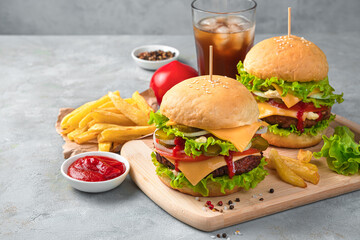 Lunch with large burgers, French fries and cola on a gray background with space to copy.