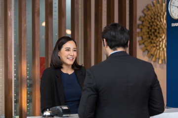 beautiful young asian woman receptionists working at a reception desk and holding credit card for customer paying. - obrazy, fototapety, plakaty