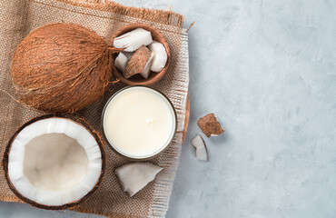 A glass of coconut milk and coconuts on a gray background. - obrazy, fototapety, plakaty