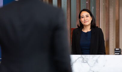 Friendly receptionist woman working at desk in hotel lobby. Leisure and travel at holidays.