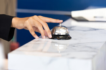 Ring bell call service with hand on hotel reception desk