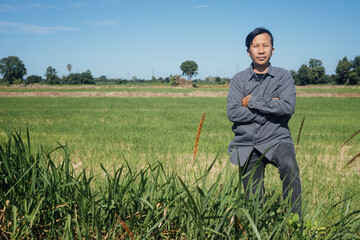 A modern farmer stands proud of his farmland in bright sunlight during the day.