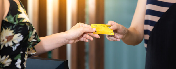 beautiful young asian woman receptionists working at a reception desk and holding credit card for customer paying.