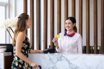 beautiful young asian woman receptionists working at a reception desk and holding credit card for...