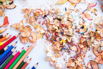 Sharpend crayons on a white background. Pencil shavings, different colors crayon pencil scrap. pencil peels. pencil sharpener