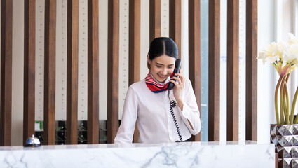 Friendly receptionist woman working at desk in hotel lobby