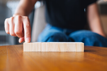 Closeup image of a hand choosing and picking seven pieces of blank wooden cube block