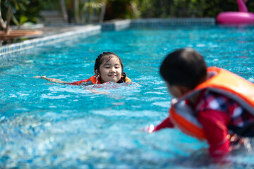 Happy Asian family vacation. Young Asian father with son and daughter enjoy by swimming pool at the...
