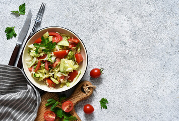 Classic vegetable salad. Salad with cabbage, cucumbers and tomatoes with lemon juice on a concrete background. View from above.