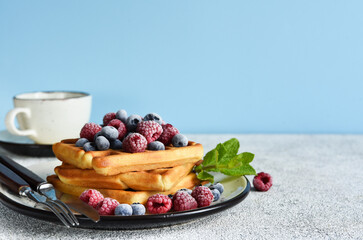 Vanilla Belgian waffles with berries and a cup of coffee for breakfast.