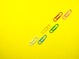 Selective focus. Paper clips arranged like the effect of a walking footprint on a yellow background with copy space.