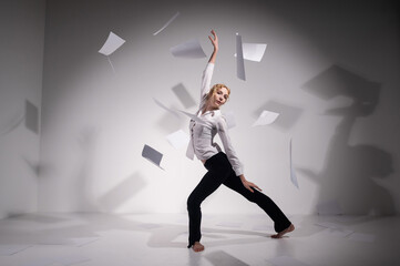 A graceful ballerina in a business suit throws documents in the studio. Business woman dance...