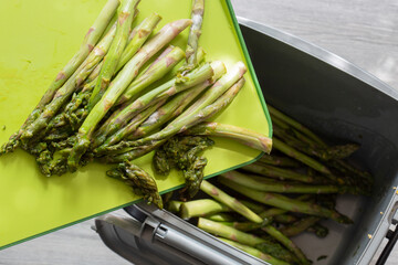 Rotten asparagus spears being thrown away into food waste recycling bin.  Food waste concept