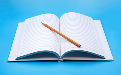 opened notebook with wooden pencil on blue background , education and knowledge concept