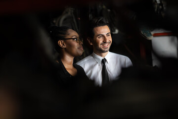 African American female worker and man customer choose and inspecting car part products while working in a old car part warehouse store.