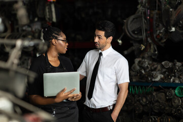 African American female worker and man customer choose and inspecting car part products while working in a old car part warehouse store.
