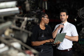 African American female worker and man customer choose and inspecting car part products while working in a old car part warehouse store.