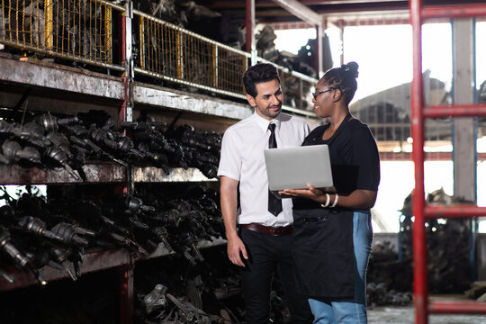 African American female worker and man customer choose and inspecting car part products while working in a old car part warehouse store.