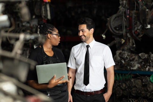 African American female worker and man customer choose and inspecting car part products while working in a old car part warehouse store.