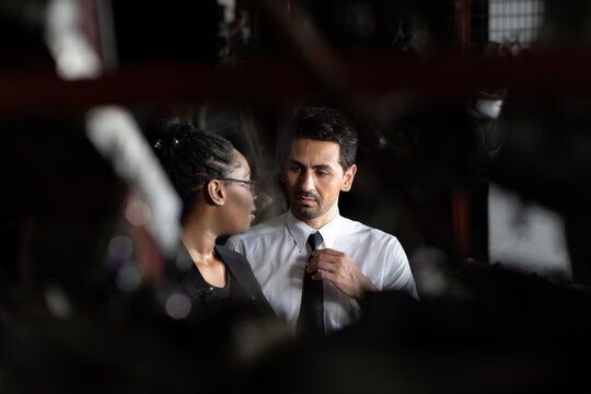 African American female worker and man customer choose and inspecting car part products while working in a old car part warehouse store.