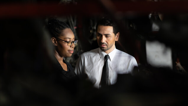 African American female worker and man customer choose and inspecting car part products while working in a old car part warehouse store.