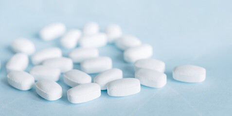 Fototapeta na wymiar White pills on a light blue background. Healthcare and medicine. 