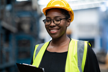 Plus size black female worker wearing safety hard hat helmet inspecting old car parts stock while...
