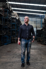Fototapeta premium Mechanical man owner small business inspecting old car parts stock on laptop computer while working in old automobile parts large warehouse