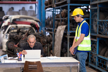 Mechanical man owner small business inspecting old car parts stock on laptop computer while working...