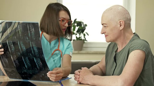 An elderly woman at the oncologist, consultation on the results of chemotherapy, good news. Young female doctor with a smile soothes and supports the patient.