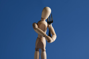 Wooden mannequin with fork on color background