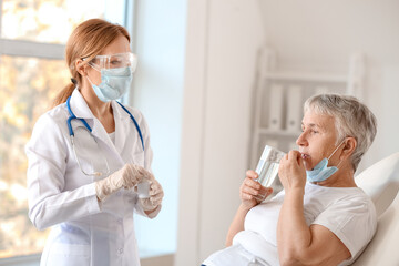 Doctor giving remedy to senior woman in clinic