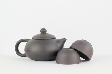 A Chinese black ceramic teapot and teacup isolated on a white background.