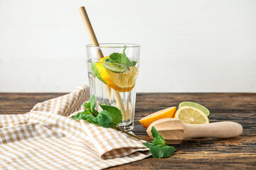 Glass of healthy lemonade and squeezer on wooden background