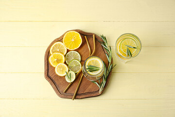 Glass of healthy lemonade and citrus fruits on color wooden background