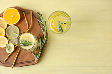 Glass of healthy lemonade and citrus fruits on color wooden background