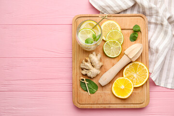 Glass of healthy lemonade and squeezer on color wooden background