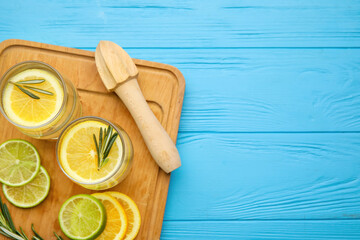 Glasses of healthy lemonade and squeezer on color wooden background