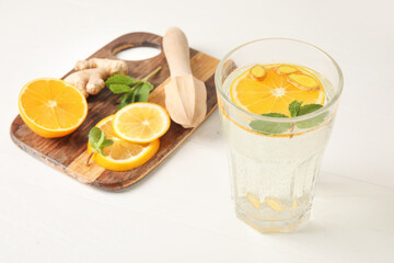 Glass of healthy lemonade on light wooden background