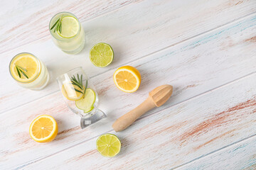 Glasses of healthy lemonade, squeezer and citrus fruits on light background