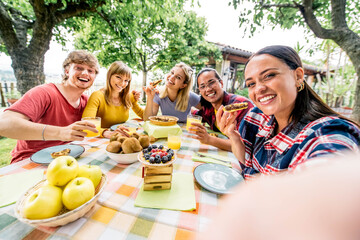 Happy multiethnic friends taking a selfie with phone at pic nic garden party - Young people having fun eating healthy food at bio organic restaurant - Friendship and youth concept