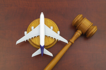 Flight cancellation, aviation law, sue airline company concept. Wooden judge gavel and airplane model on wooden background.