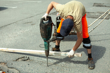 He removes the asphalt with a jackhammer. Removing the asphalt layer from the road.