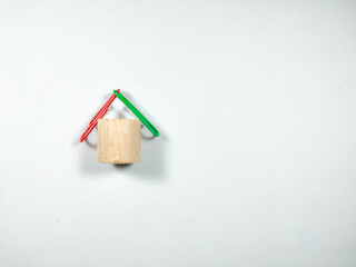 Colorful paper clips and block cylinders arranged like a house on a white background with copy space.