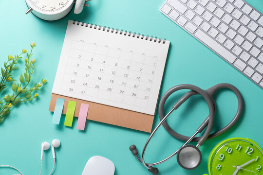 close up of calendar, computer and stethoscope on the green table background, planning for healthy and doctor meeting concept
