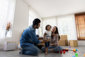 Happy family in living room. Cute daughter with parent. Moving new house a lot of parcel box. Father mother and daughter relax together at home in the morning.